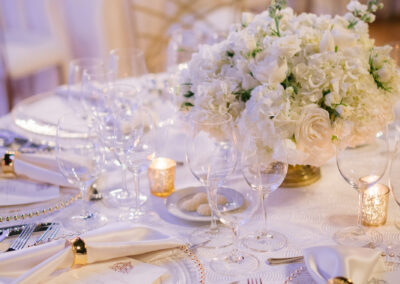 all white wedding table settings at indoor luxury reception